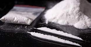 buying Cocaine online in Canada, this is a photo of cocaine powder on a table divided in two lines with more in a medical plastic