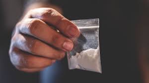 buying Cocaine online in Canada. this is a photo of a cocaine dealer's fingers holding a few grams of coke in a medical plastic.